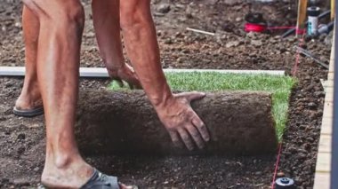 Çimenlik Yuvarlayan Adam. Çim yapıyorum. Yavaş bir hareket yap. Tanımlanamayan bahçıvan elleri yeşil çimlerden mükemmel bir çim oluşturuyor. Peyzaj tasarımı üzerinde çalışan kişi.