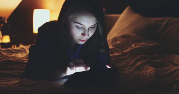 夜にタブレットPcを使用して女性 スローモーション4K Dci 若い100万人の消費者のオンラインショッピング自宅から ベッドの上に横たわっている 日常生活における技術 — ストック動画