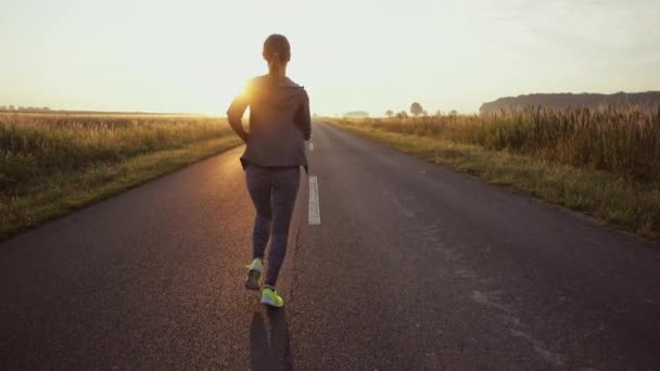 屋外で走っているランナーの女性 日当たりの良い道路でトレーニングしながら裸足のスポーツシューズを履いてスポーツ女性 スローモーション レンズフレア — ストック動画