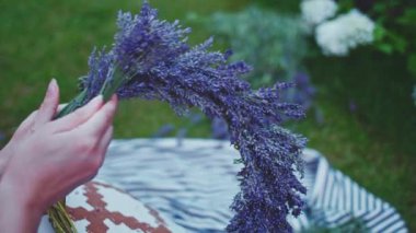 Lavanta Çelengi Yapan Kadın. Yavaş bir hareket yap. Tanınmayan kadın çiçekçi elleri saf lavanta çiçekleriyle süsleme yapıyor. Provence Fransız bahçesinde huzurlu bir gecenin tadını çıkaran bir kız..