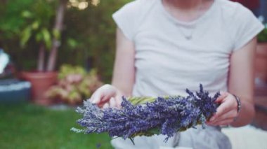 Lavanta Çelengi Yapan Kadın. Yavaş bir hareket yap. Tanınmayan kadın çiçekçi elleri saf lavanta çiçekleriyle süsleme yapıyor. Provence Fransız bahçesinde huzurlu bir gecenin tadını çıkaran bir kız..