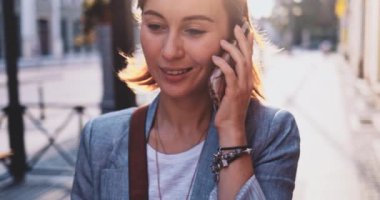 Genç İşkadını Akıllı Telefon Kullanıyor, Güneşli Sabah Şehrinde İşe Gidiyor. Yavaş hareket, Gimbal Dengeleyici. Şehirde cep telefonu olan çekici, profesyonel bir iş kadını. Mercek Fişeği.