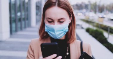 Koruyucu Maskeli İş Kadını Şehirde Dolaşan Akıllı Telefon Kullanıyor. Yavaş hareket Gimbal dengelendi. Hava kirliliği ve koronavirüse karşı tıbbi maskeli kadın girişimci Covid19 şebekesi