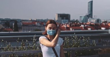 Nefes almak için tıbbi maskeyi çıkaran genç bir kadın. Yavaş hareket, Gimbal Dengeleyici. Kadın hava kirliliği ve koronavirüse karşı yüz maskesi çıkarıyor. Salgının sonu. Özgürlük, temiz hava.