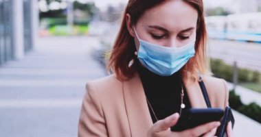 Koruyucu Maskeli İş Kadını Şehirde Dolaşan Akıllı Telefon Kullanıyor. Yavaş hareket Gimbal dengelendi. Hava kirliliği ve koronavirüse karşı tıbbi maskeli kadın girişimci Covid19 şebekesi