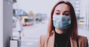 Şehirde koruyucu maske takan bir iş kadınının portresi. Yavaş hareket Gimbal dengelendi. Hava kirliliği ve koronavirüse karşı maske takan öğrenci..