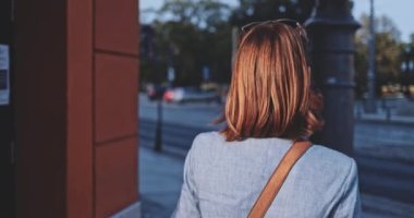 Şehirde koruyucu bir maske takan bir kadın. Yavaş hareket, Gimbal Dengeleyici. Hava kirliliği ve Coronavirus Covid-19 'a karşı maskeli genç bir kadın sokakta dolaşıyor. Şehir Sabahı.