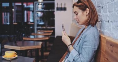 Bir kafede akıllı telefon kullanan genç bir kadın. Yavaş hareket, dengeleyici. Business Woman bir kafede sosyal medya için videolar çekiyor, iletişim kuruyor, kişisel markasını oluşturuyor, çevrimiçi. Hayatta teknoloji.