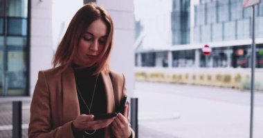 Tabletli bir iş kadını şehirde akıllı telefondan konuşuyor. Yavaş hareket Gimbal dengelendi. Genç Profesyonel Kadın sabah aceleyle ofise geliyor. Kadın girişimci şebekesi