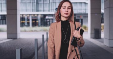 Tabletli ve akıllı telefonlu iş kadını şehirde yürüyor. Yavaş hareket Gimbal dengelendi. Genç Profesyonel Kadın sabah aceleyle ofise geliyor. Finans Bölgesi.