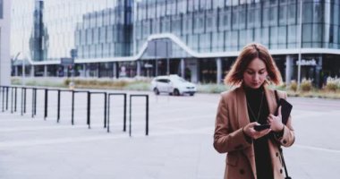 Şehirde Dolaşan Akıllı Telefon Kullanan İş Kadını. Yavaş hareket Gimbal dengelendi. İnternette kadın girişimci ağı, daktilo, mesaj, öğrenme, sabah ofise koşuşturma.