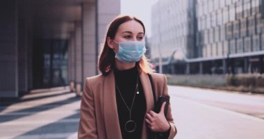 Şehirde koruyucu maske takan bir iş kadınının portresi. Yavaş hareket Gimbal dengelendi. Hava kirliliği ve koronavirüse karşı maske takan öğrenci..