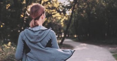 Güneşli şehir parkında koşan koşucu kadın dışarıda egzersiz yapıyor. Gimbal sabitlendi, yavaşlama hareketi yapıldı. Sporcu Kadın Sabah Koşu Eğitimi. Sağlıklı yaşam tarzı. Lens fişeği. Dikkatli Koşu, Gülümseme, Rahatlama.