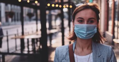Şehirde koruyucu bir maske takan bir kadın. Yavaş hareket, Gimbal Dengeleyici. Hava kirliliği ve Coronavirus Covid-19 'a karşı maskeli genç bir kadın sokakta dolaşıyor. Şehir Sabahı.