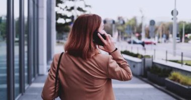 Tabletli bir iş kadını şehirde akıllı telefondan konuşuyor. Yavaş hareket Gimbal dengelendi. Genç Profesyonel Kadın sabah aceleyle ofise geliyor. Kadın girişimci şebekesi