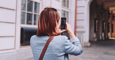 Şehirde akıllı telefon kullanan, video çeken genç bir kadın. Yavaş hareket, Gimbal Dengeleyici. Kadın Blogcu Sosyal Medya için İçerik Oluşturuyor. Yayın hizmetleri, ağ kurma takıntısı. Avrupa seyahati.