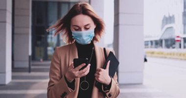 Koruyucu Maskeli İş Kadını Şehirde Dolaşan Akıllı Telefon Kullanıyor. Yavaş hareket Gimbal dengelendi. Hava kirliliği ve koronavirüse karşı tıbbi maskeli kadın girişimci Covid19 şebekesi