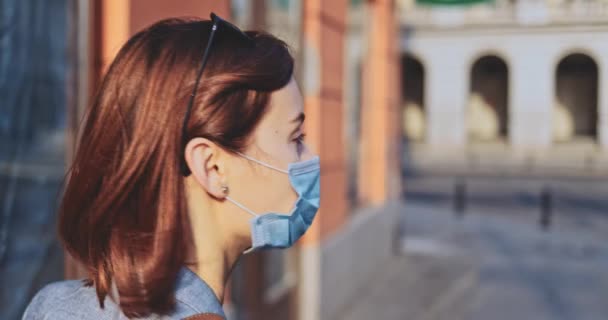 Femme portant un masque protecteur marchant dans la ville. Lentement, stabilisateur de cardan. Jeune Femme au masque facial contre la pollution de l'air et le coronavirus Covid-19, dans la rue. Matin urbain. — Video