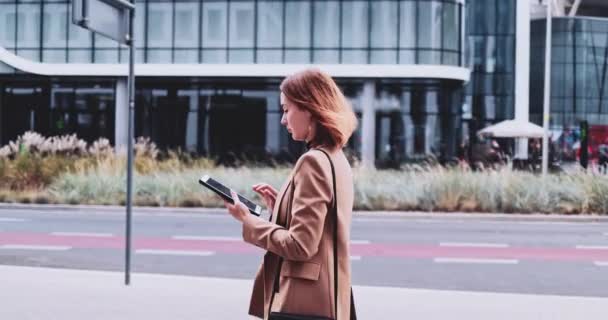 デジタルタブレットを使って街を歩くビジネスウーマン。スローモーションジンバル安定化。インターネットで女性起業家ネットワーク,入力,テキストメッセージ,オンライン学習,午前中にオフィスに急いで. — ストック動画