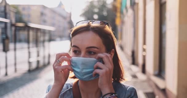 Mujer quitándose la máscara protectora para respirar en la ciudad. Movimiento lento, estabilizador Gimbal. Máscara de niña en la cara contra la contaminación del aire y coronavirus Covid-19, fuera y alrededor en una calle. — Vídeo de stock