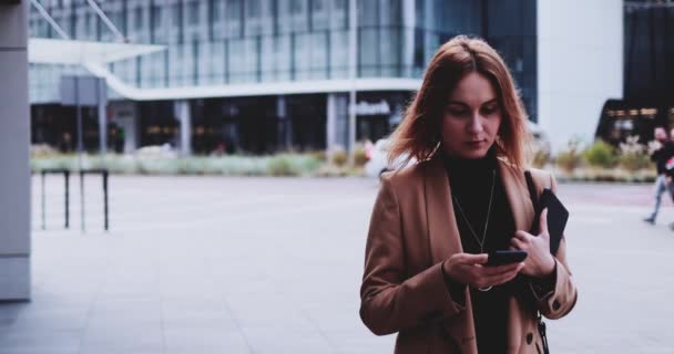 Mujer de negocios usando Smartphone caminando en la ciudad. Movimiento lento Gimbal estabilizado. Empresaria femenina en red en Internet, mecanografía, mensajes de texto, aprendizaje en línea, corriendo a la oficina por la mañana. — Vídeos de Stock