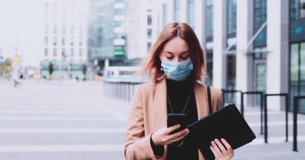 Mujer de negocios en máscara protectora Use Smartphone Walking In The City. Movimiento lento Gimbal estabilizado. Empresaria femenina en mascarilla médica contra la contaminación atmosférica y el coronavirus Covid19 networking — Vídeo de stock