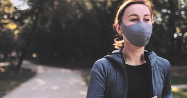 Бігунка жінка, що носить захисну маску, бігає у парку Санні. Гімбал ВИЗНАЄТЬСЯ, СЛУЖЕ ПОТРІБНО. Спортсмен в масці для обличчя проти забруднення повітря і Covid19 Morning Jogging. — стокове відео