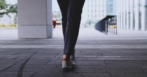 Невідома жінка ноги в кросівок, що йдуть на тротуарі. Постріл стабілізатора Джімбала. Жіночі ноги в міському модному спортивному взутті роблять швидкі кроки на бруківці вуличного тротуару в місті — стокове відео