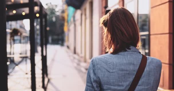 Jeune femme d'affaires utilisant SmartPhone, Aller travailler dans la ville ensoleillée du matin. Lentement, stabilisateur de cardan. Femme d'affaires professionnelle attrayante avec un téléphone portable dans une ville. Lentille Flare. — Video