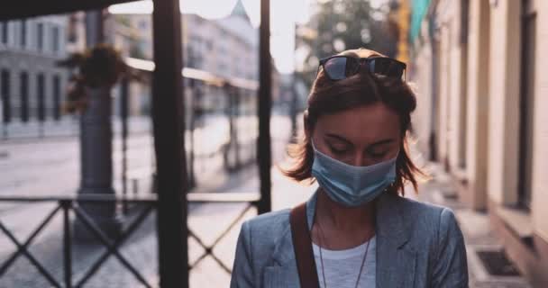 Femme portant un masque protecteur marchant dans la ville. Lentement, stabilisateur de cardan. Jeune Femme au masque facial contre la pollution de l'air et le coronavirus Covid-19, dans la rue. Matin urbain. — Video