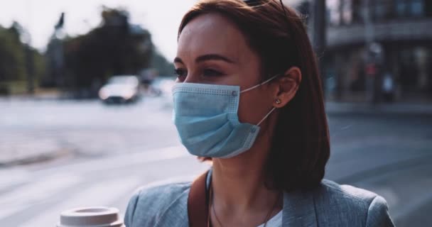 Γυναίκα με προστατευτική μάσκα, πίνει καφέ, περπατάει στην πόλη. Αργή κίνηση. Νεαρή γυναίκα βγάλε μια μάσκα προσώπου κατά της ατμοσφαιρικής ρύπανσης και του ιού coronavirus covid-19 για να πιεις από ένα χαρτί.. — Αρχείο Βίντεο