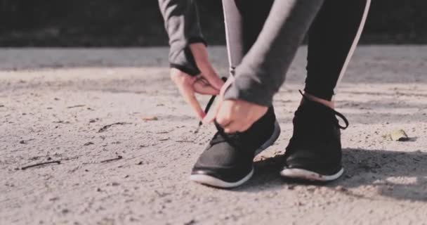 Mujer irreconocible atando cordones zapatillas de running. GIMBAL DE MOVIMIENTO Lento ESTABILIAZADO. Atleta femenina prepárate para correr en el parque en zapatillas minimalistas descalzas. Estilo de vida deportivo saludable. — Vídeos de Stock