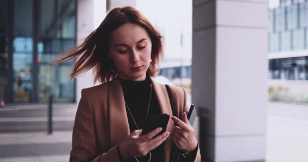 Mujer de negocios con Tablet hablando en Smartphone caminando en la ciudad. Movimiento lento Gimbal estabilizado. Joven profesional hembra corriendo a la oficina por la mañana. Red de mujeres empresarias — Vídeo de stock