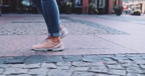 Donna irriconoscibile gambe in scarpe da ginnastica camminare sul pavimento. SLOW MOTION Stabilizzatore Gimbal shot. Piedi femminili in scarpe sportive di moda urbana che fanno passi veloci su un marciapiede di ciottoli in città — Video Stock