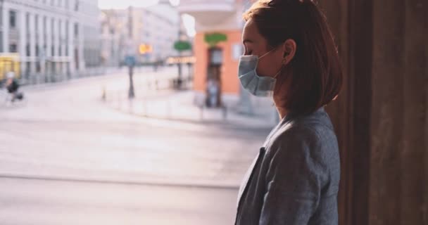 Жінка носить захисну маску, яка ходить по місту. SLOW MOTION, Gimbal Stabilizer. Молода жінка в масці перед лицем проти забруднення повітря і коронавірусу Ковід-19, на вулиці і навколо. Міський ранок. — стокове відео