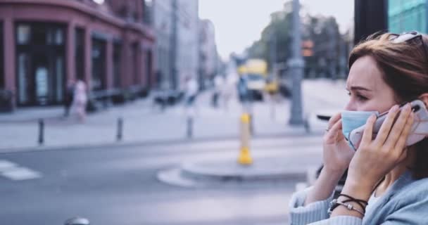 Хвора жінка носить захисну маску, яка співає, ходить у місті, розмовляє по смартфонах. СЛОВЛЕННЯ, стабілізатор Джимбала. Молода жінка в масці для обличчя проти забруднення повітря і коронавірусу Ковід-19 . — стокове відео