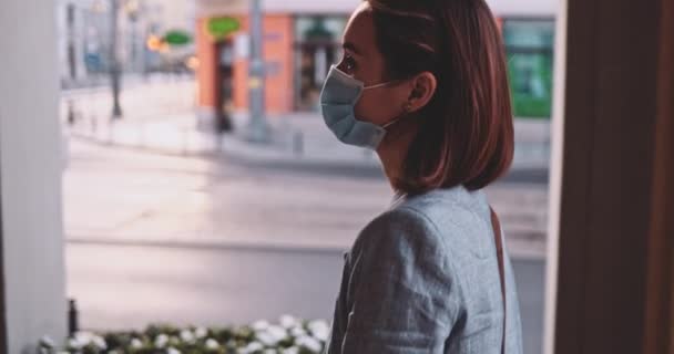 Женщина в защитной маске гуляет по городу. Медленное движение, стабилизатор Гимбала. Молодая женщина в маске против загрязнения воздуха и коронавируса Ковид-19, на улице. Городское утро. — стоковое видео