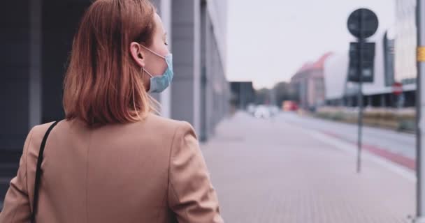 Mujer de negocios con una máscara protectora caminando por la ciudad. Movimiento lento Gimbal estabilizado. Joven profesional en una mascarilla médica contra la contaminación del aire y el coronavirus Covid19 desplazamientos. — Vídeos de Stock