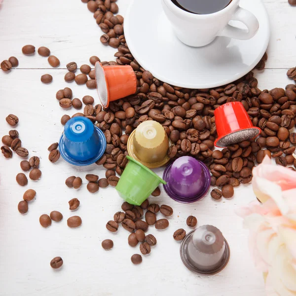 Colorful coffee capsules with coffee beans on white wooden table top view