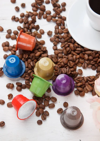 Colorful coffee capsules with coffee beans on white wooden table top view