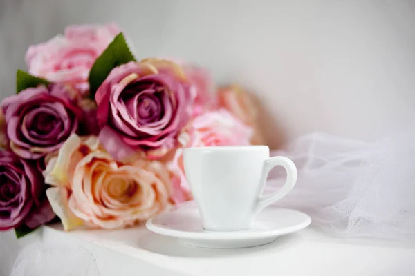 White coffee cup with rose flowers on white background