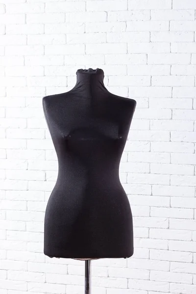 Antique dress form mannequin on white brick wall background