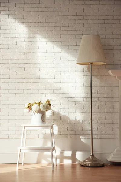 White loft interior with white brick wall, lamp and flowers with wooden furniture