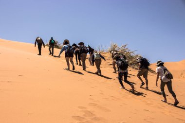 Çöl kumuluna tırmanan insanların başlığı