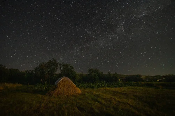 Un pajar bajo un oscuro cielo nocturno estrellado — Foto de Stock