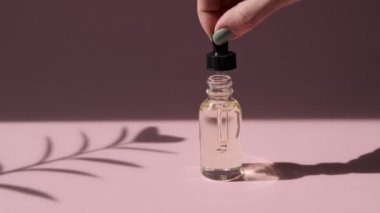Cilt bakımı esansı yağ damlası şişesi pembe arka plan. Sıvı serumu, yüz derisi için vitamin. Düşüş