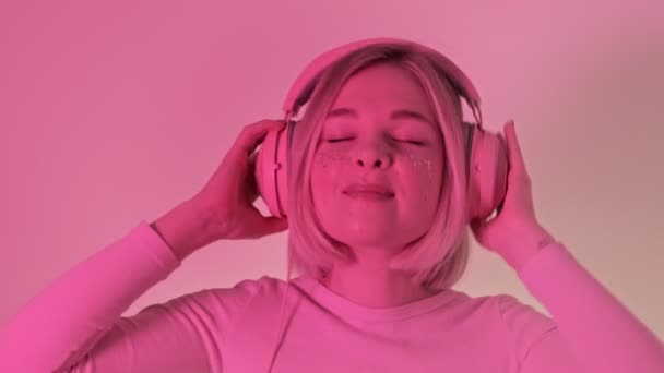 Kvinna Rosa Neonljus Lyssnar Musik Hörlurar Njuter Och Dansar Blundar — Stockvideo