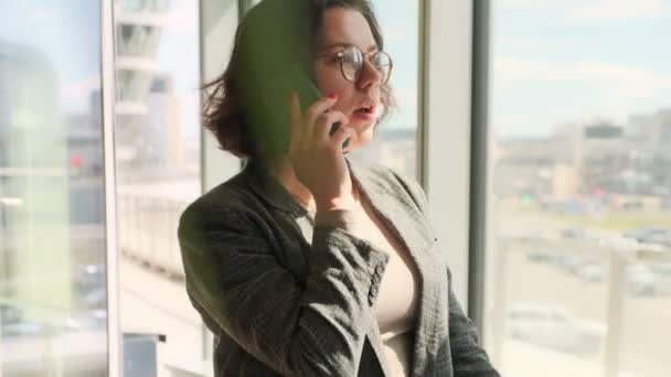 ビジネスの女性はモダンなオフィスで電話で話しています 成功した女性は 携帯電話でクライアントと通信します リモート通信 — ストック動画