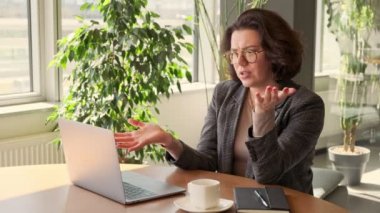 Web kamerasında görüntülü görüşme. İş kadını rahat bir ofiste dizüstü bilgisayarından video konuşması yapıyor. Canlı yayın, giysi ve mesafe çalışması. Çalışan röportajı..
