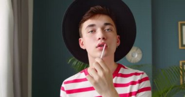 Makyaj ruju ya da dudak parlatıcısı kullanan genç bir homo aynaya bakar gibi kameraya bakmaya hazırlanıyor. Güzellik blogcusu hipster makyaj videosu hazırlıyor.